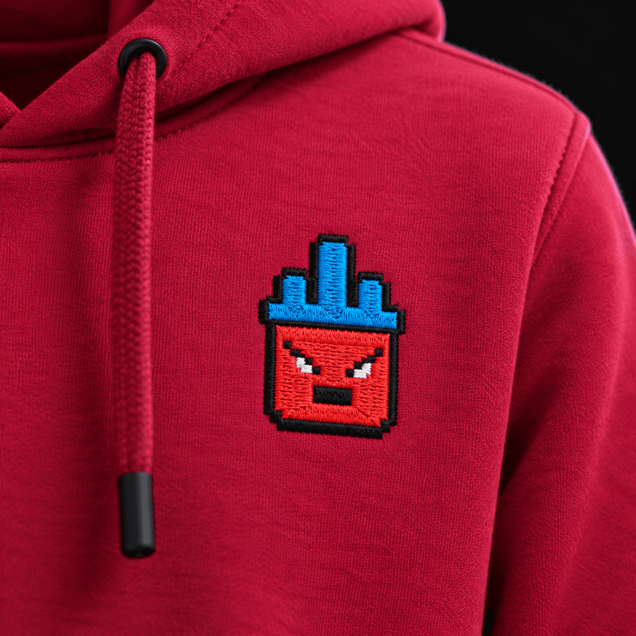 Close-up of the embroidery: red pixel robot with a blue crown, stitch by stitch on the fabric
